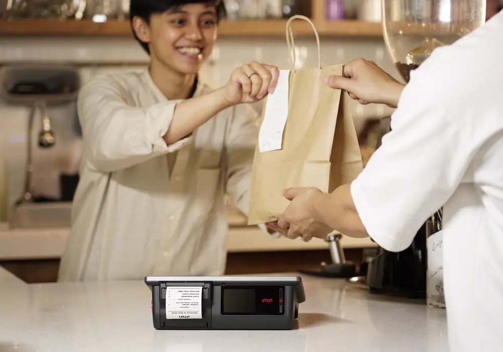 Una cajera le entrega la bolsa a un cliente sobre el mostrador